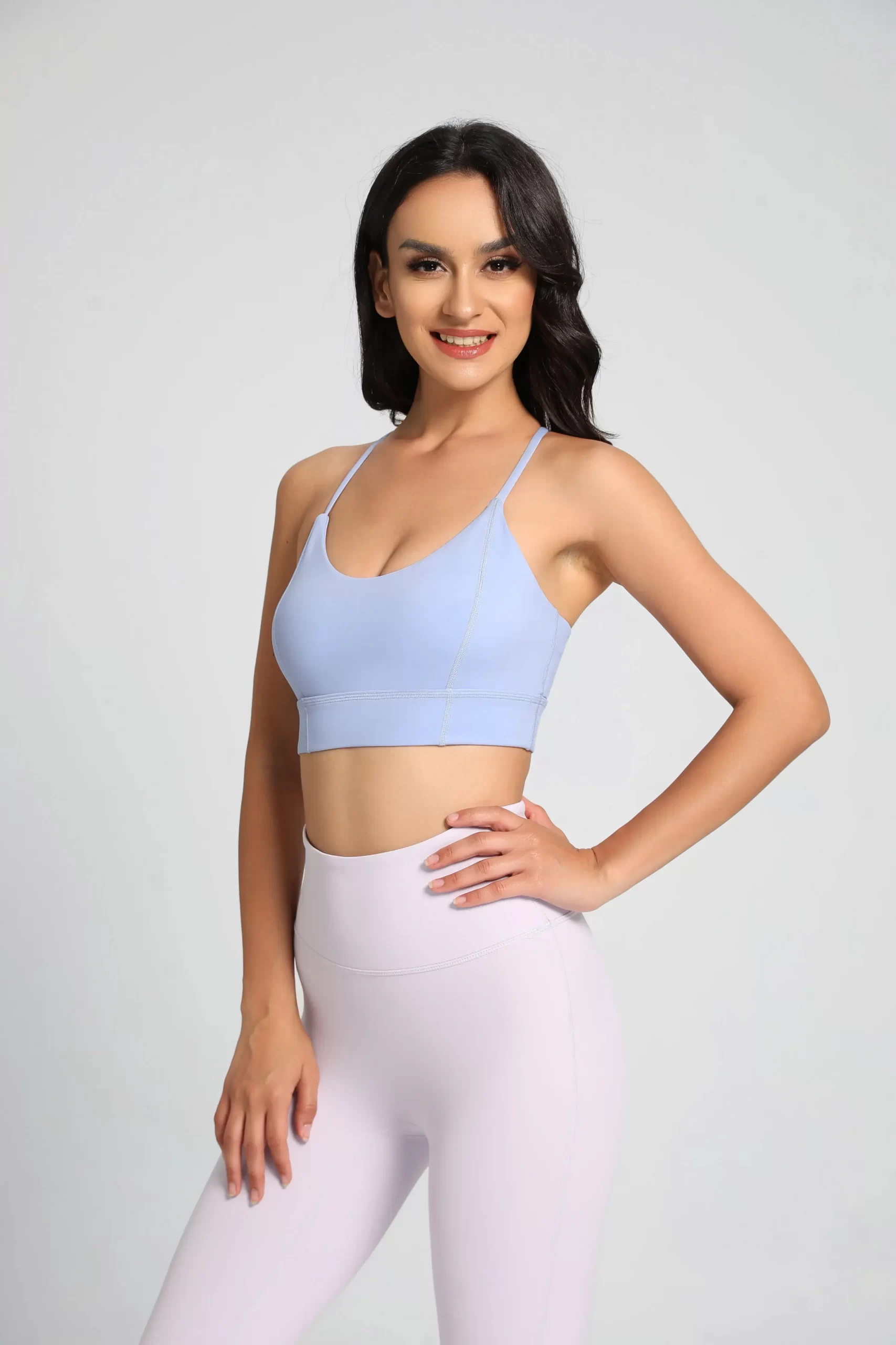 Woman in a pastel blue sports bra and white high-waisted leggings, showcasing a minimalistic workout look.